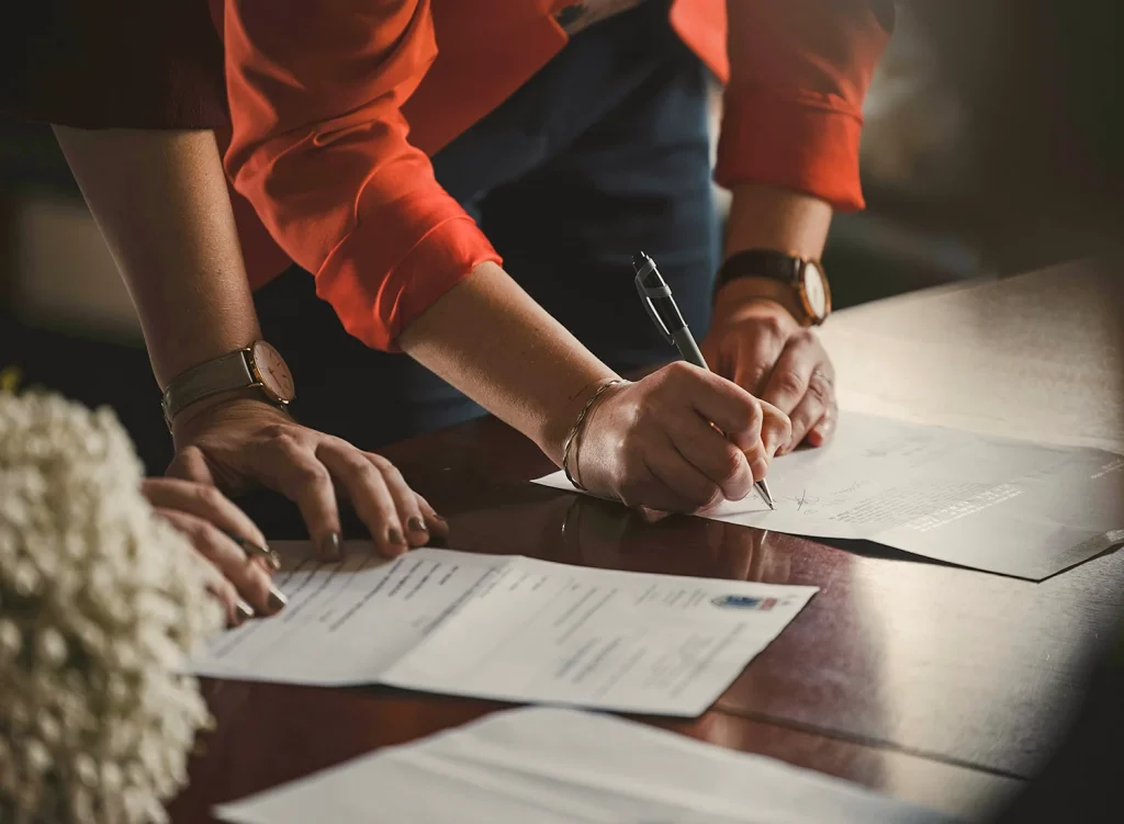 Visuel - Droit Sécurité sociale Deux femmes dont on ne voit que les mains signent des documents (photo © Romain Dancre - Unsplash)